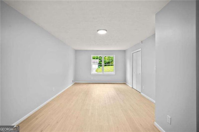 spare room featuring wood finished floors, baseboards, and a textured ceiling