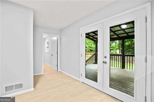 doorway featuring light wood-type flooring, visible vents, baseboards, and french doors