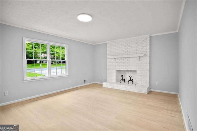 unfurnished living room with baseboards, a brick fireplace, wood finished floors, and crown molding