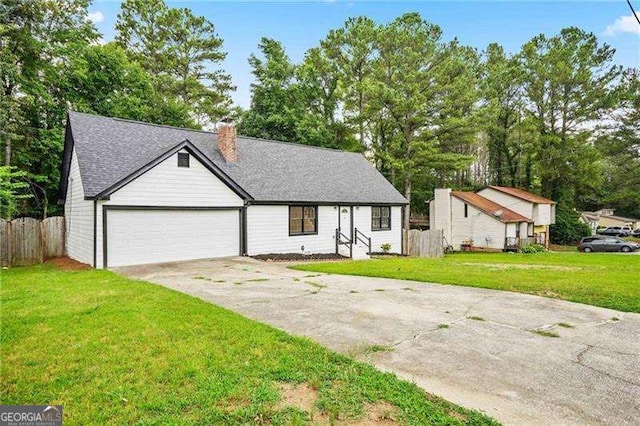 view of front of house with fence, concrete driveway, a front yard, a chimney, and an attached garage