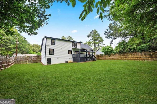 rear view of property with a fenced backyard and a yard