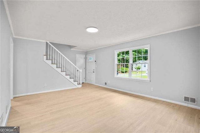 interior space with stairway, light wood-style flooring, visible vents, and ornamental molding