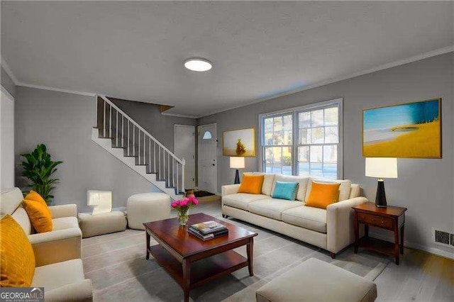 living area featuring stairs, visible vents, crown molding, and light wood finished floors