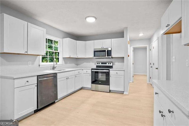 kitchen with white cabinetry, light countertops, appliances with stainless steel finishes, and a sink