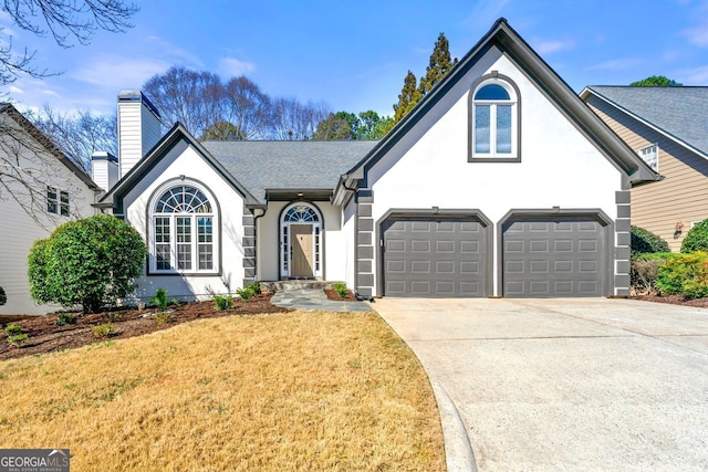 view of front of home with concrete driveway, a front lawn, a chimney, and stucco siding