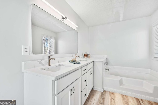 full bath featuring a sink, a garden tub, wood finished floors, and double vanity