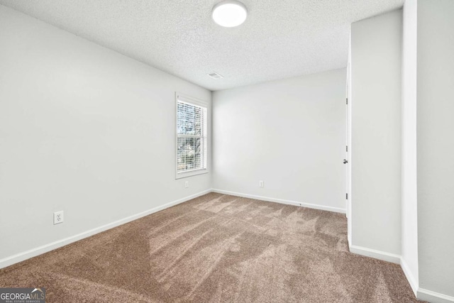 spare room with carpet, baseboards, and a textured ceiling