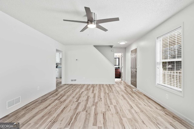 unfurnished living room featuring light wood-style floors, a ceiling fan, visible vents, and a textured ceiling