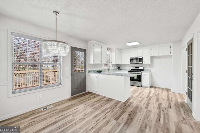 kitchen featuring appliances with stainless steel finishes, white cabinetry, light wood-type flooring, and a peninsula