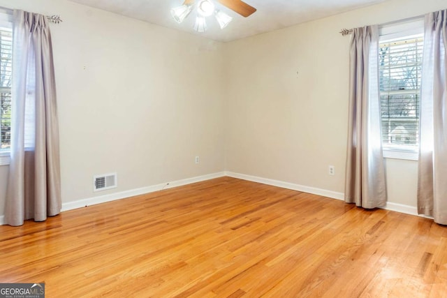 spare room with a ceiling fan, a healthy amount of sunlight, visible vents, and light wood finished floors