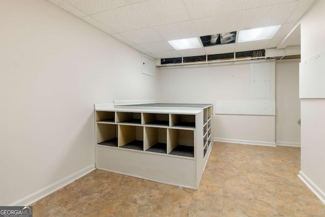 interior space with a paneled ceiling and baseboards