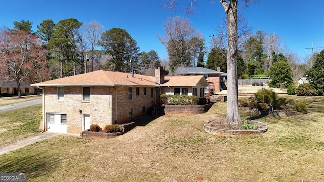 back of house featuring a yard, brick siding, and a chimney