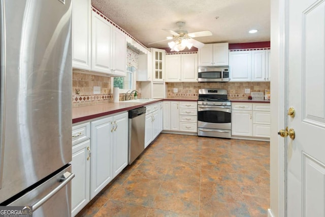 kitchen featuring backsplash, appliances with stainless steel finishes, white cabinetry, and a sink