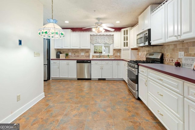 kitchen with a sink, tasteful backsplash, appliances with stainless steel finishes, baseboards, and ceiling fan