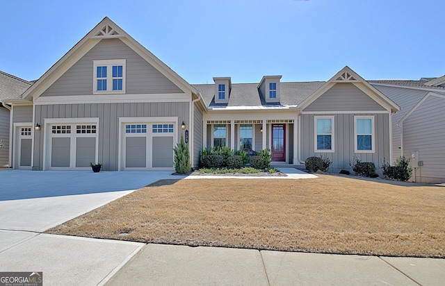 view of front facade with board and batten siding, a shingled roof, driveway, and a front lawn