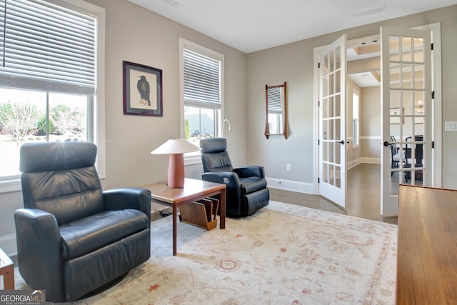 living area with french doors, baseboards, visible vents, and wood finished floors