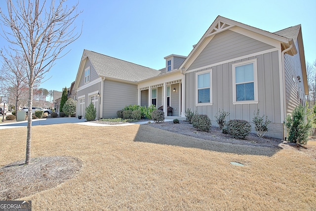 view of front of home featuring a porch, an attached garage, concrete driveway, a front lawn, and board and batten siding