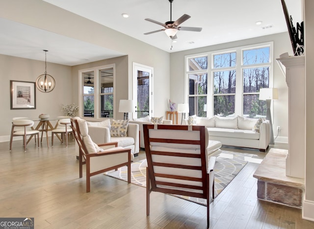 living area with visible vents, baseboards, recessed lighting, ceiling fan with notable chandelier, and wood finished floors