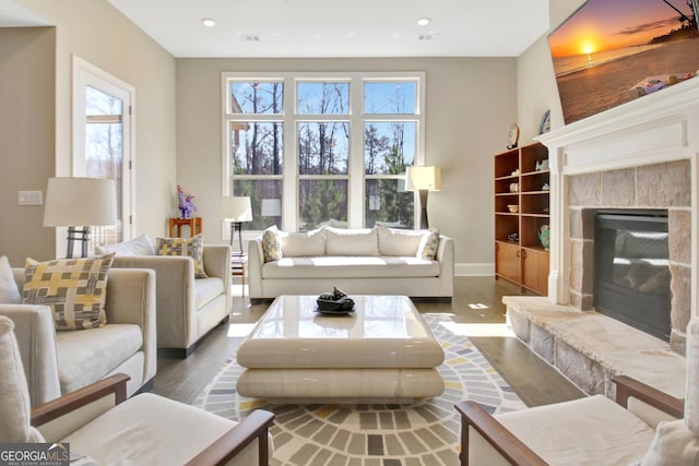 living area with recessed lighting, a premium fireplace, baseboards, and wood finished floors