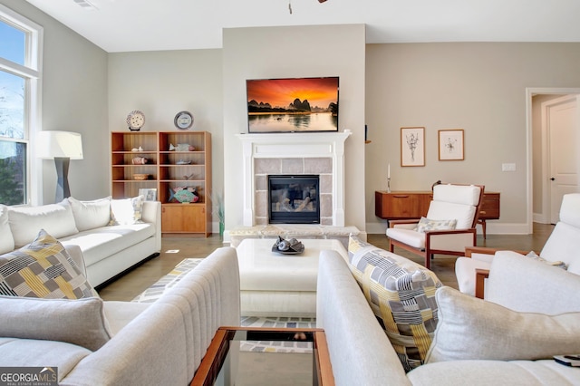 living room with a tile fireplace, baseboards, and wood finished floors