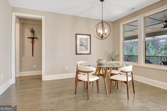 dining space featuring visible vents, ceiling fan with notable chandelier, baseboards, and wood finished floors