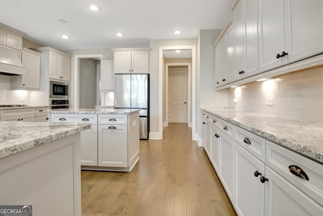 kitchen with white cabinetry, recessed lighting, light wood-style floors, appliances with stainless steel finishes, and decorative backsplash