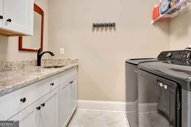 laundry area with a sink, baseboards, cabinet space, and washing machine and clothes dryer