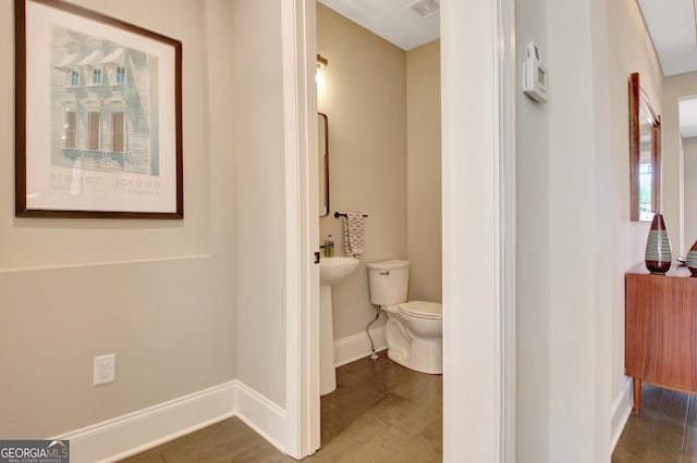 bathroom featuring toilet, wood finished floors, and baseboards