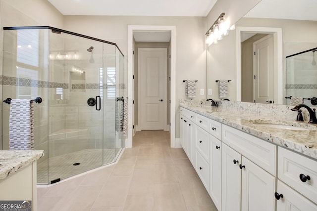 full bathroom featuring a sink, a stall shower, double vanity, and tile patterned flooring