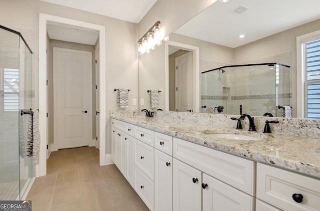 bathroom featuring visible vents, double vanity, a stall shower, a sink, and tile patterned floors