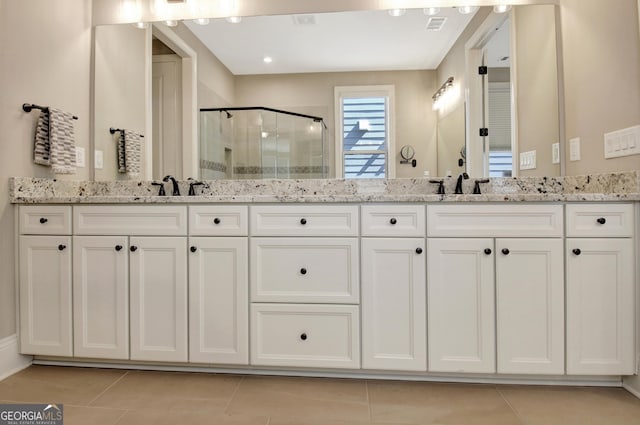 bathroom featuring double vanity, a stall shower, a sink, and tile patterned flooring