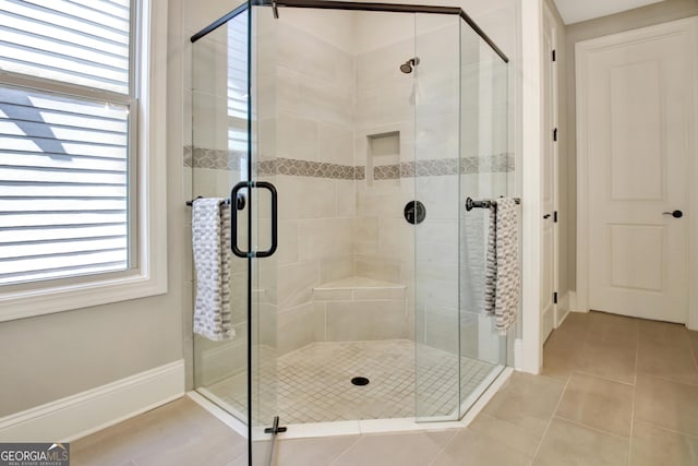 bathroom featuring tile patterned floors, a stall shower, and baseboards