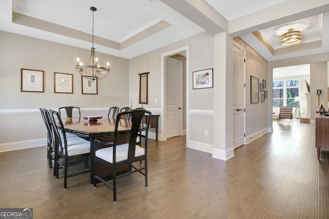 dining area featuring a tray ceiling, baseboards, an inviting chandelier, and dark wood-style floors