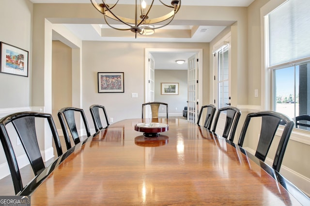 dining room with an inviting chandelier, baseboards, and a raised ceiling