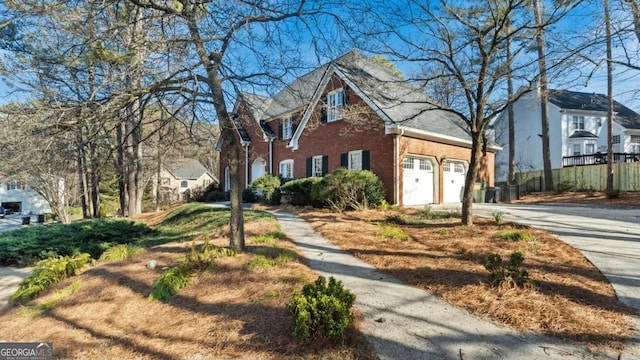 view of front of home with a garage, brick siding, driveway, and fence