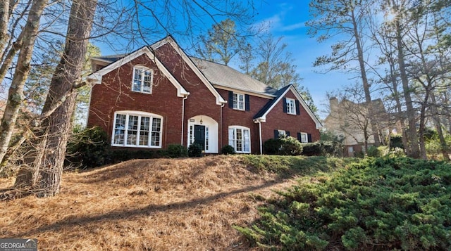 colonial-style house with a shingled roof and brick siding