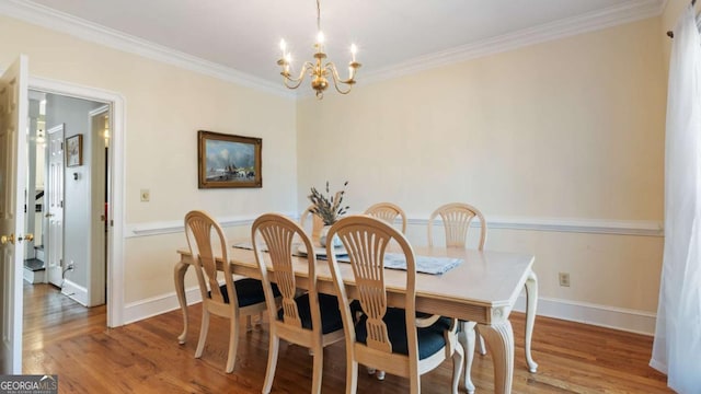 dining area with an inviting chandelier, wood finished floors, baseboards, and ornamental molding