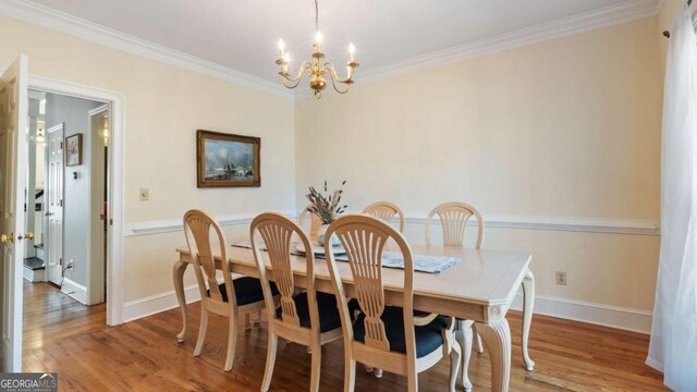 dining area featuring baseboards, crown molding, wood finished floors, and a chandelier