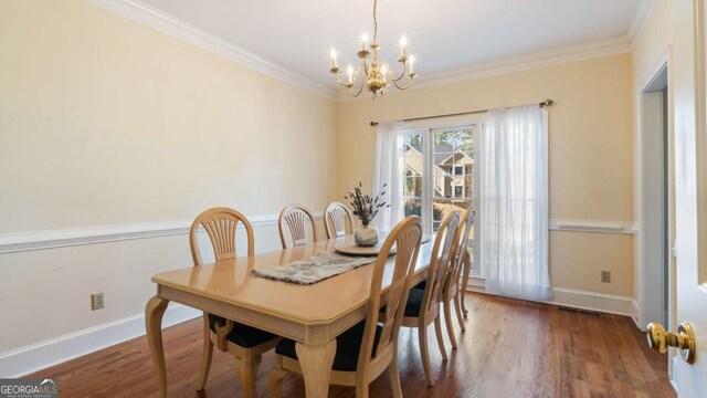 dining space with baseboards, a notable chandelier, wood finished floors, and ornamental molding