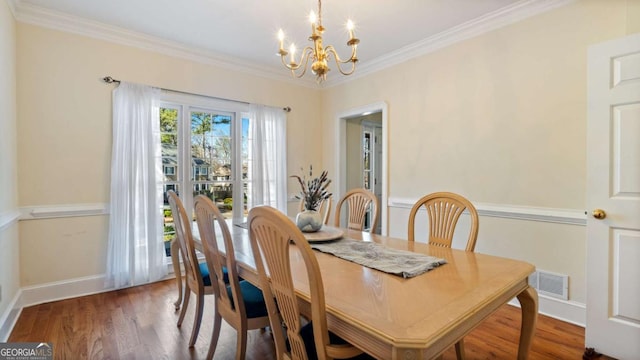 dining space with a notable chandelier, ornamental molding, visible vents, and wood finished floors