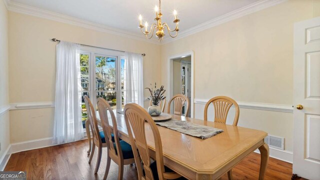 dining area featuring visible vents, ornamental molding, a chandelier, and wood finished floors