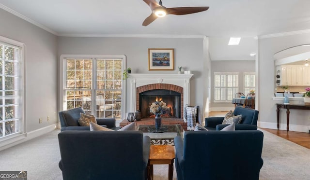 living room featuring a wealth of natural light, baseboards, a brick fireplace, and ornamental molding