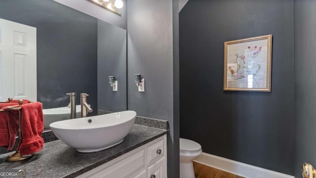 bathroom with baseboards, toilet, wood finished floors, and vanity