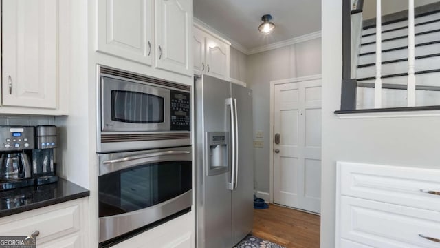 kitchen with tasteful backsplash, crown molding, stainless steel appliances, wood finished floors, and white cabinetry