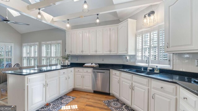 kitchen with white cabinetry, vaulted ceiling, a sink, dishwasher, and a peninsula