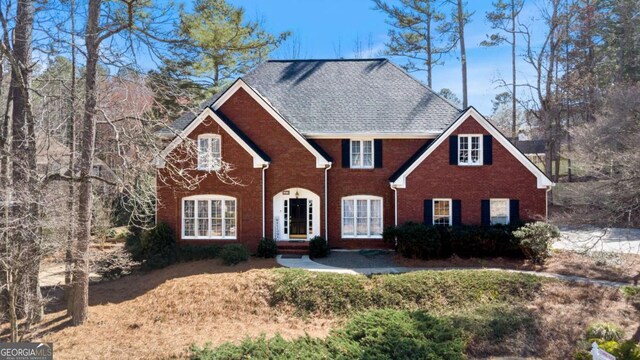 view of front of home featuring brick siding and roof with shingles