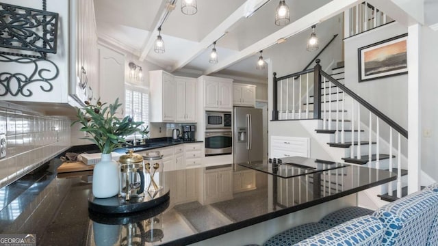 kitchen featuring a sink, stainless steel appliances, white cabinets, dark countertops, and a kitchen breakfast bar