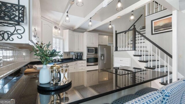 kitchen featuring white cabinets, stainless steel appliances, dark countertops, a sink, and a kitchen breakfast bar