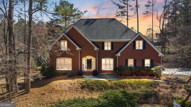 view of front of house with brick siding, concrete driveway, a garage, and fence