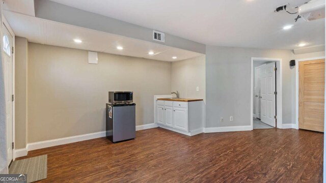 kitchen featuring stainless steel microwave, dark wood-type flooring, baseboards, and visible vents